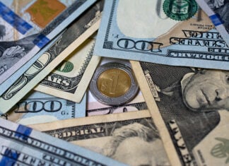 The peso dips under 17.5 to the US dollar, its strongest level since 2024 Dollar bills surround a one-peso coin